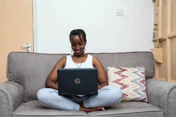 A woman working on a laptop on a sofa at home in Nairobi