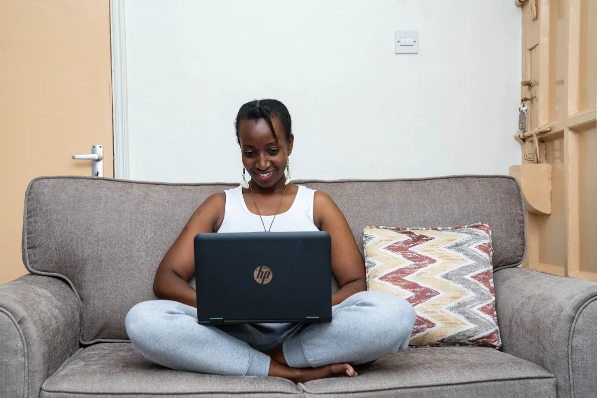A woman working on a laptop on a sofa at home in Nairobi
