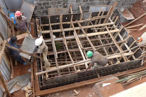 Three workers building concrete formwork on a construction site in Nairobi