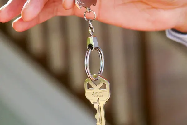 A hand holding a house key on a keyring