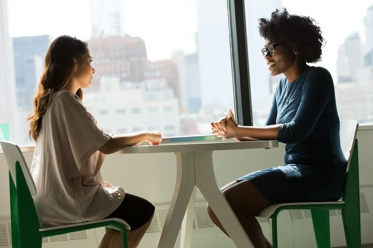 Two women talking across a table, as in a job interview