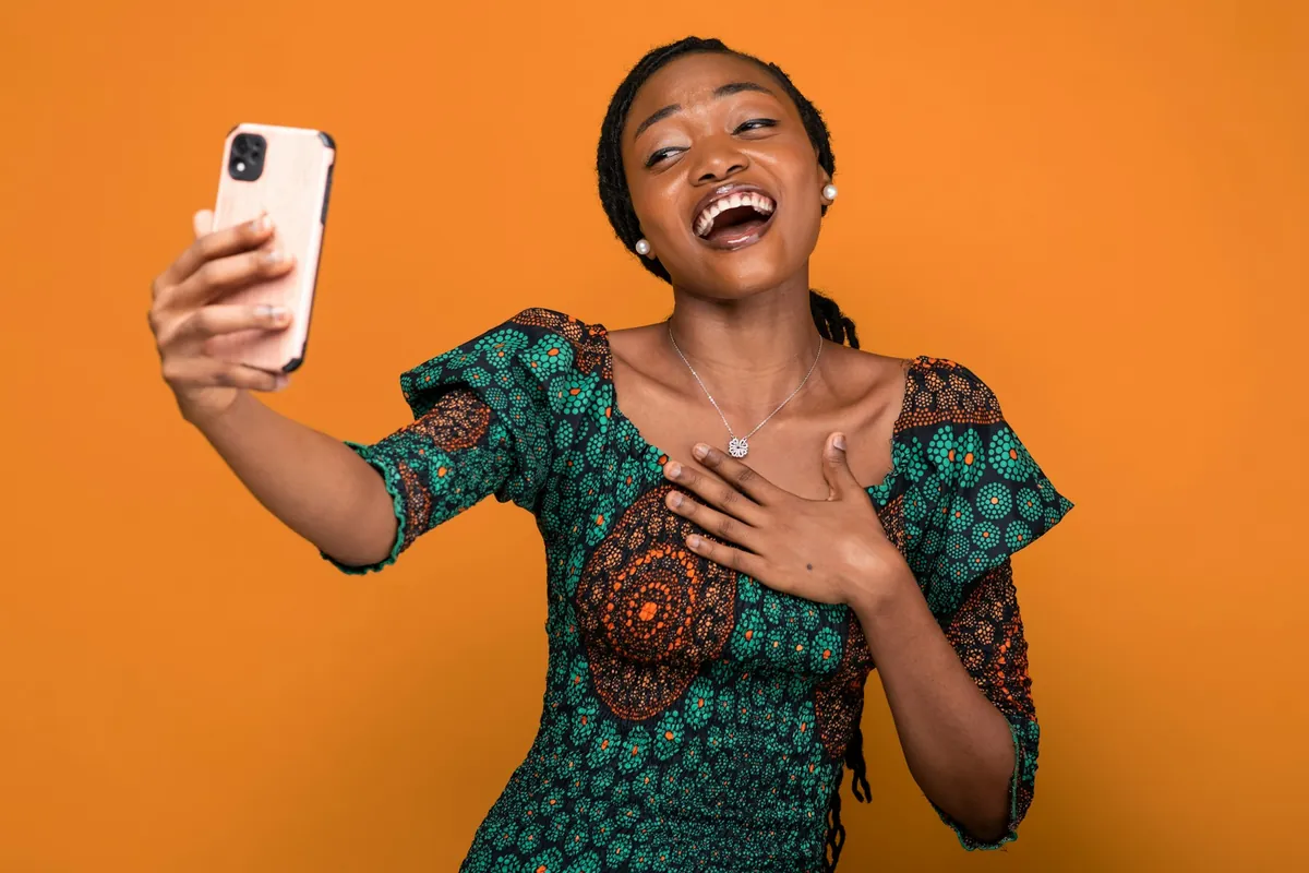 A laughing young woman taking a selfie on her phone