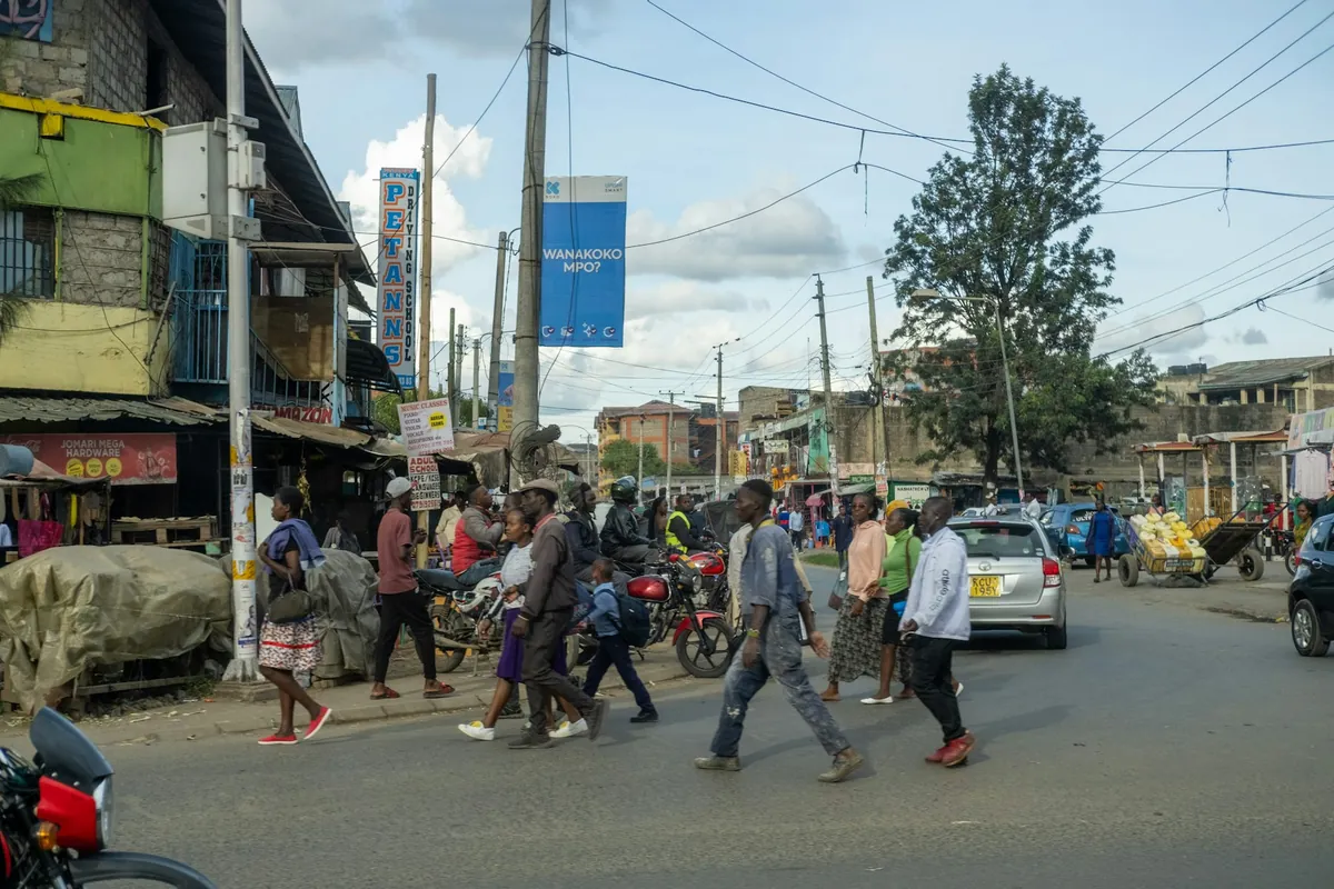 People walking along a busy street with shops and motorbikes
