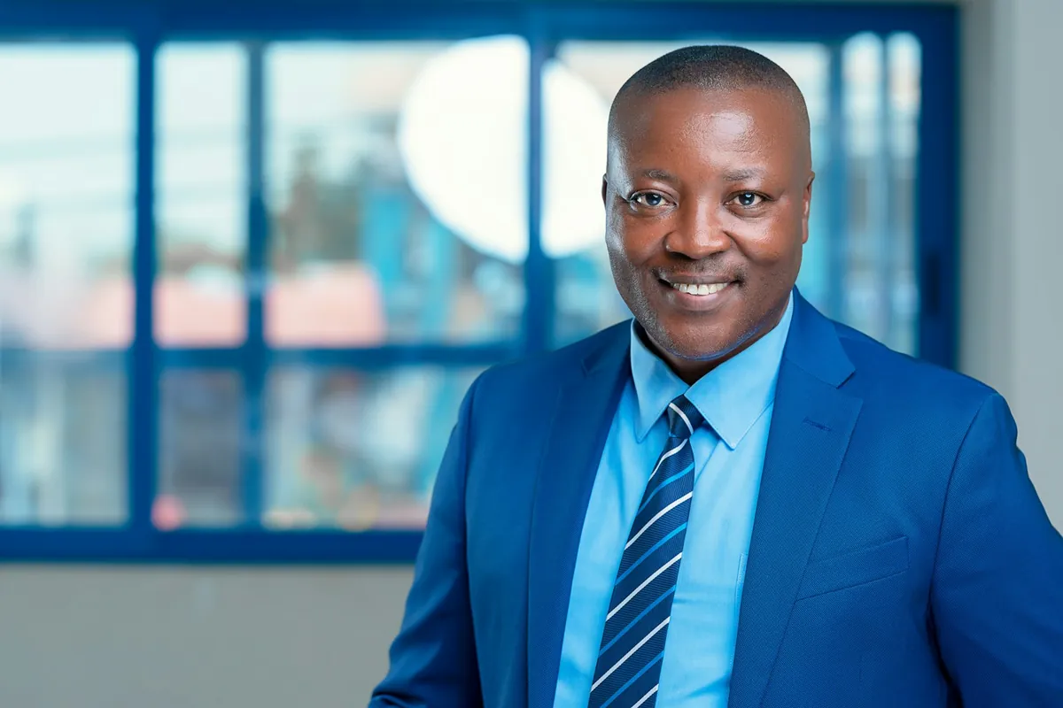 A smiling salesman in a blue suit and tie in an office