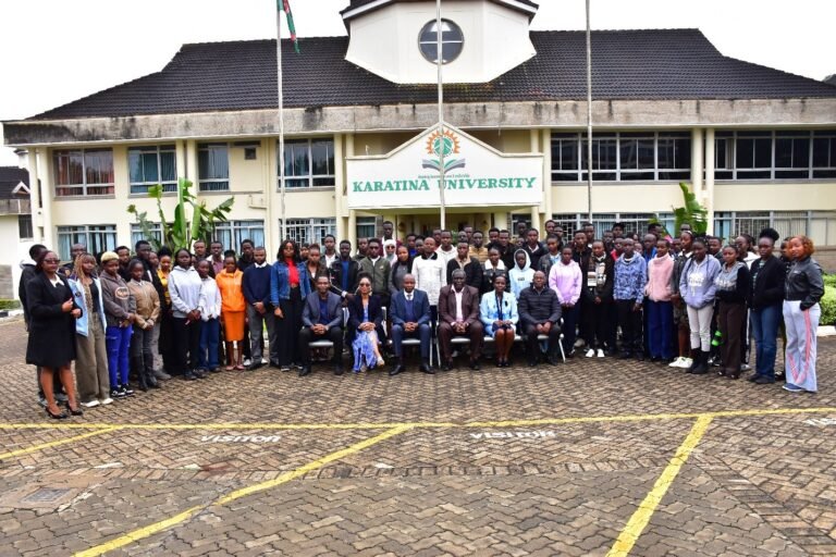 Delegates at a Karatina University conference in front of a modern glass building